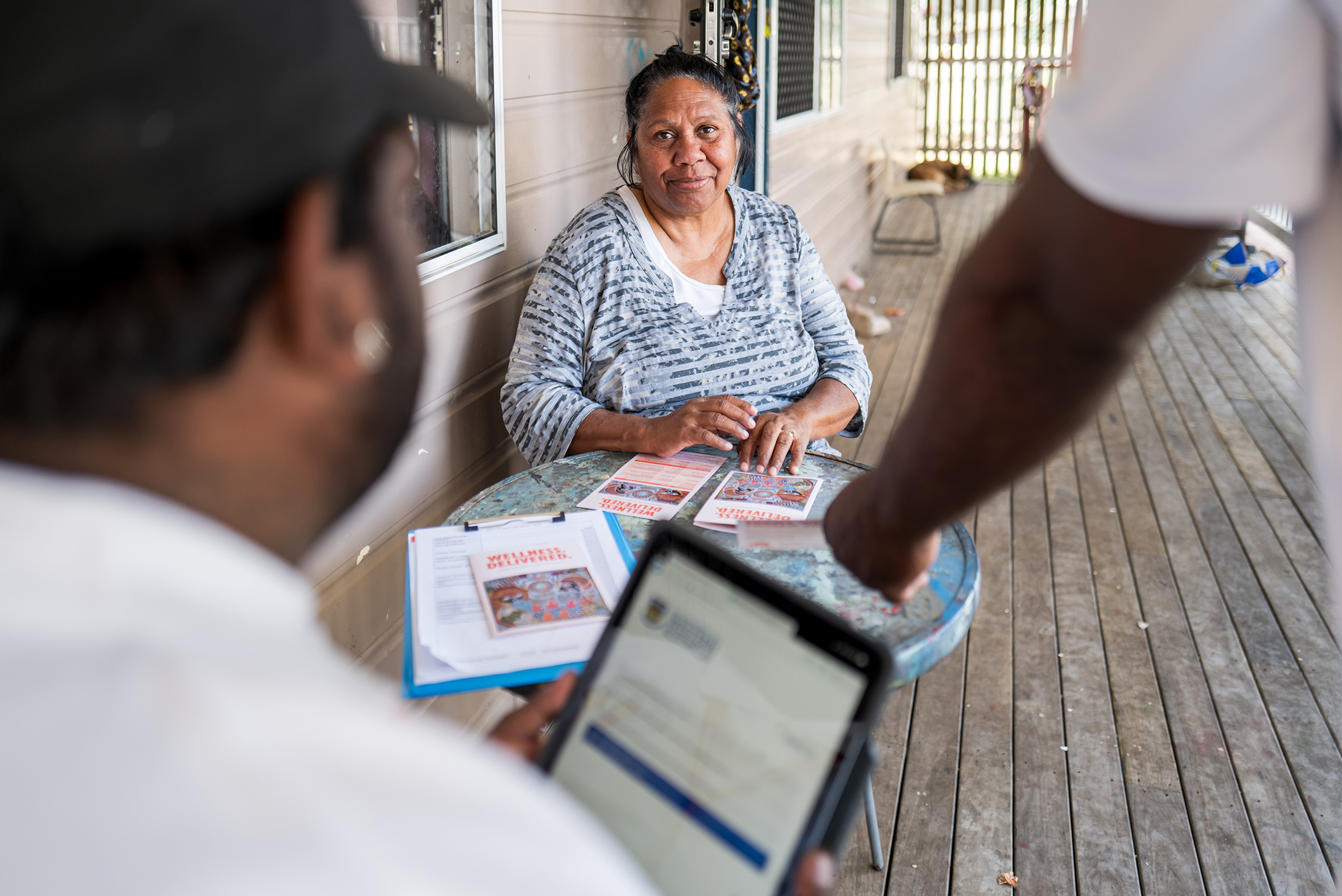 Aboriginal woman sitting outside her house talking to People Connector