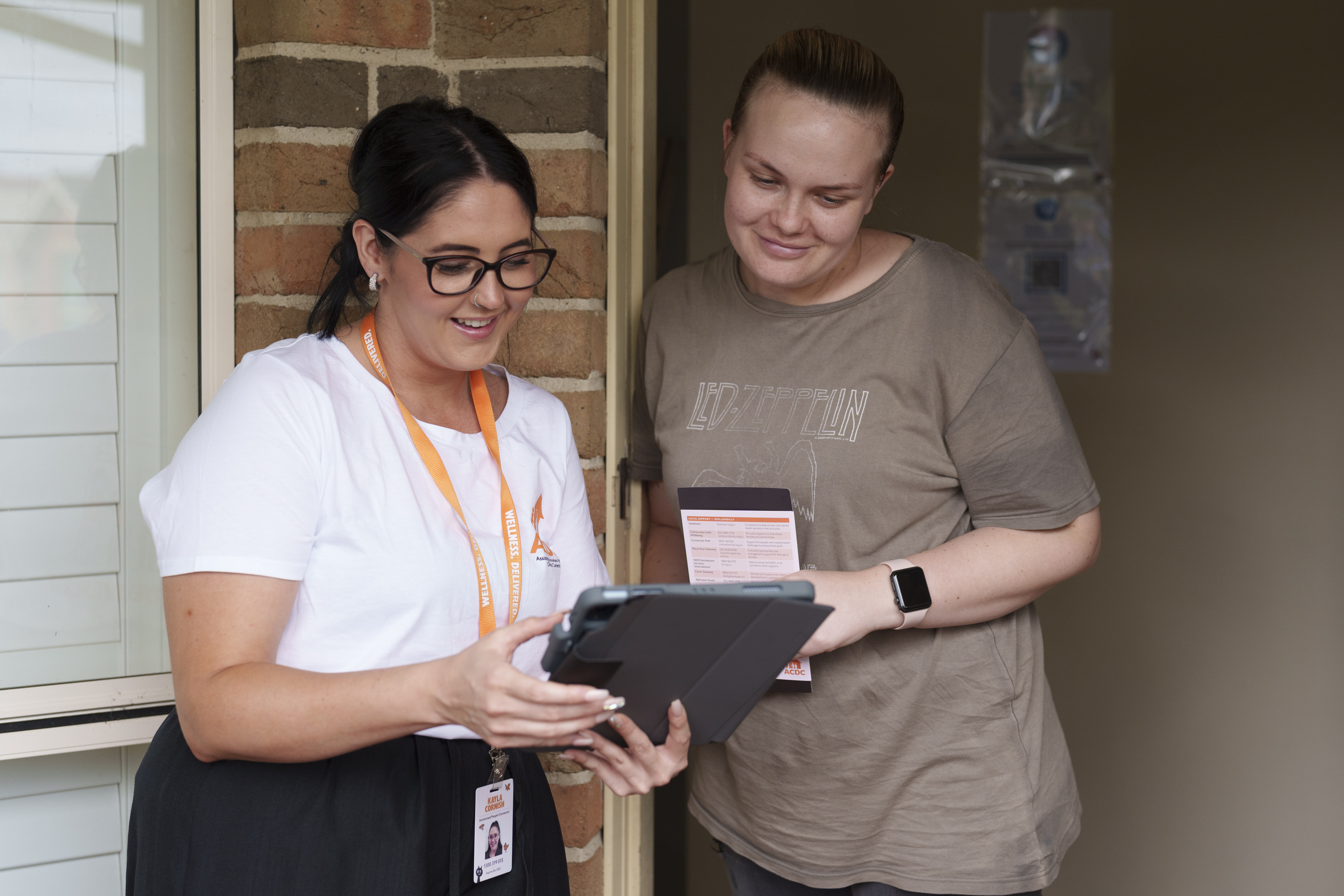 People Connector with participant at the door filling out a survey