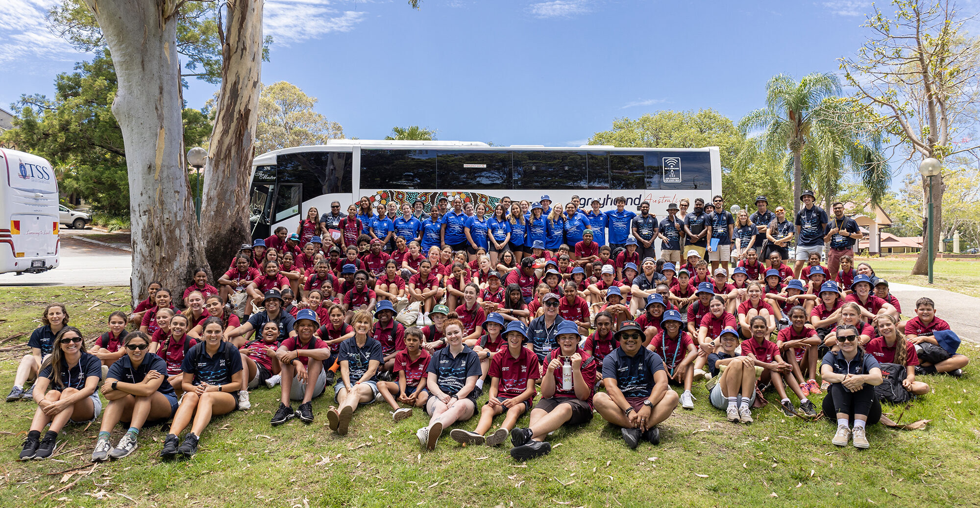 Big group of Yalari students in front of bus sitting on the lawn