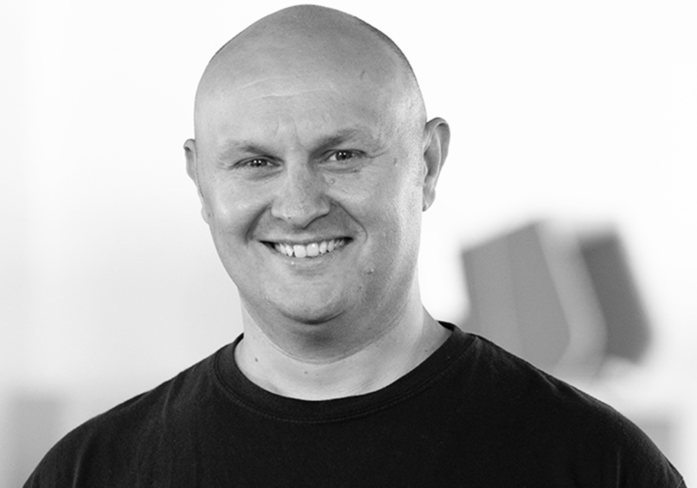 Photo of a man with a black shirt. He is staring at the camera.