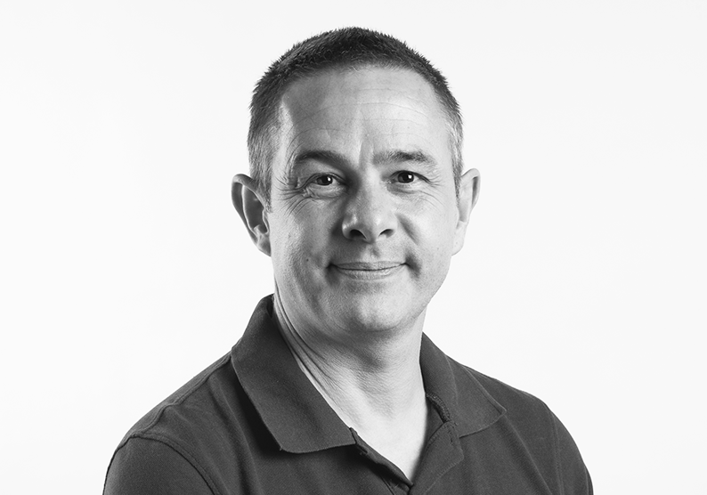 Photo of Ian Down. He has short dark hair, and is wearing a dark polo shirt He is smiling at the camera.